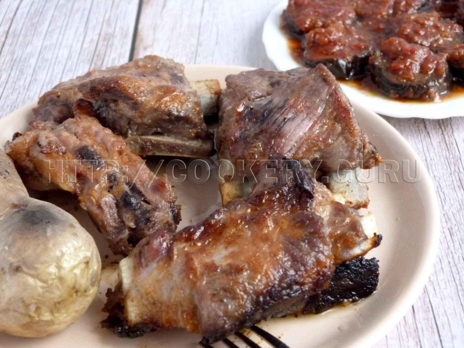 запеченные свиные ребрышки, запеченные свиные ребрышки на блюде с картошкой и баклажанами